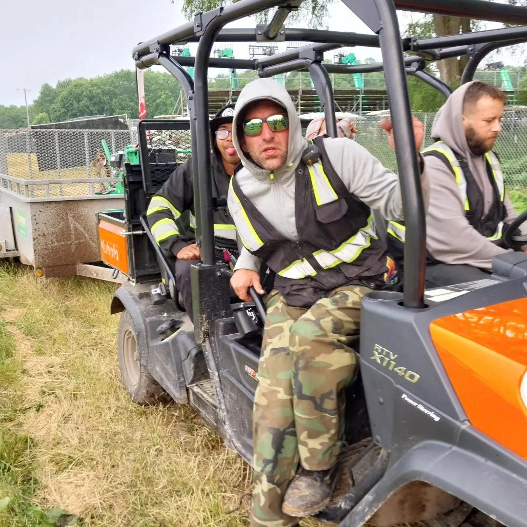 Three men on utility vehicle in reflective vests