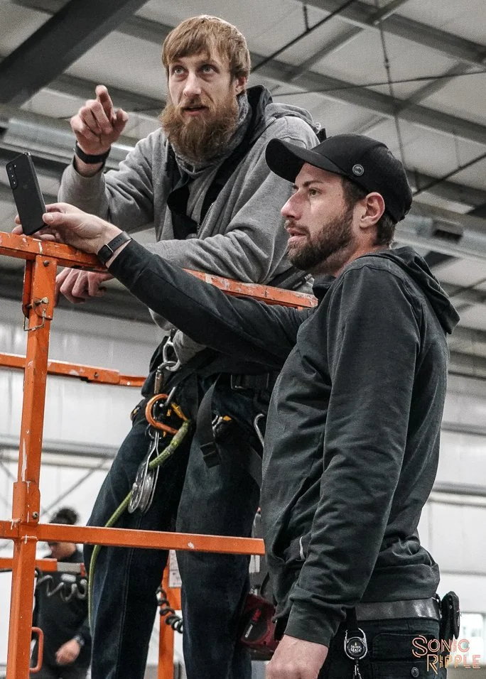 Two men standing on scaffolding in industrial setting