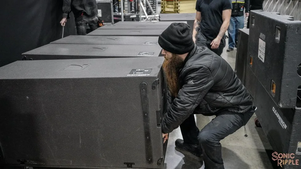 Man adjusting large black speaker at event